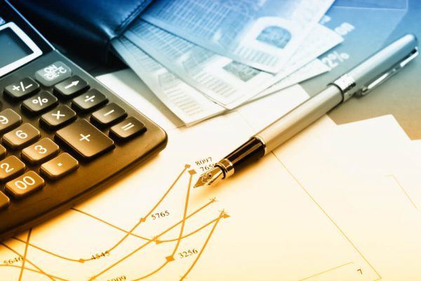 Calculadora ao lado de caneta sobre papeis diversos