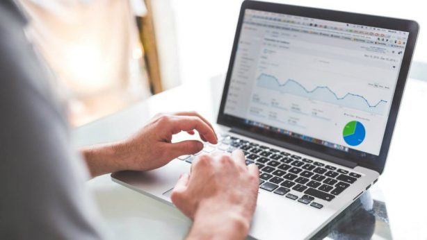 Homem usando notebook com tela mostrando gráficos