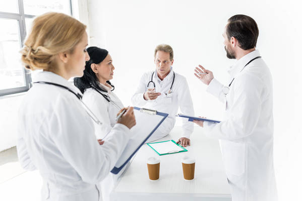 Quatro médicos conversando e anotando coisas na prancheta
