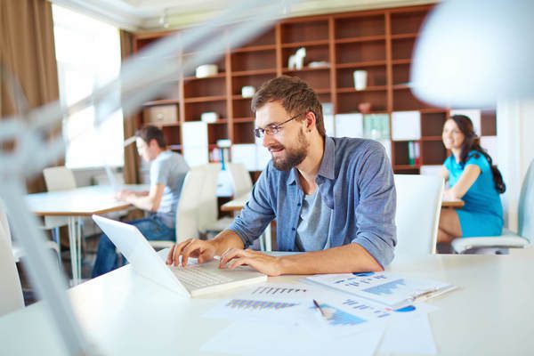 Homem usando notebook com gráficos ao lado