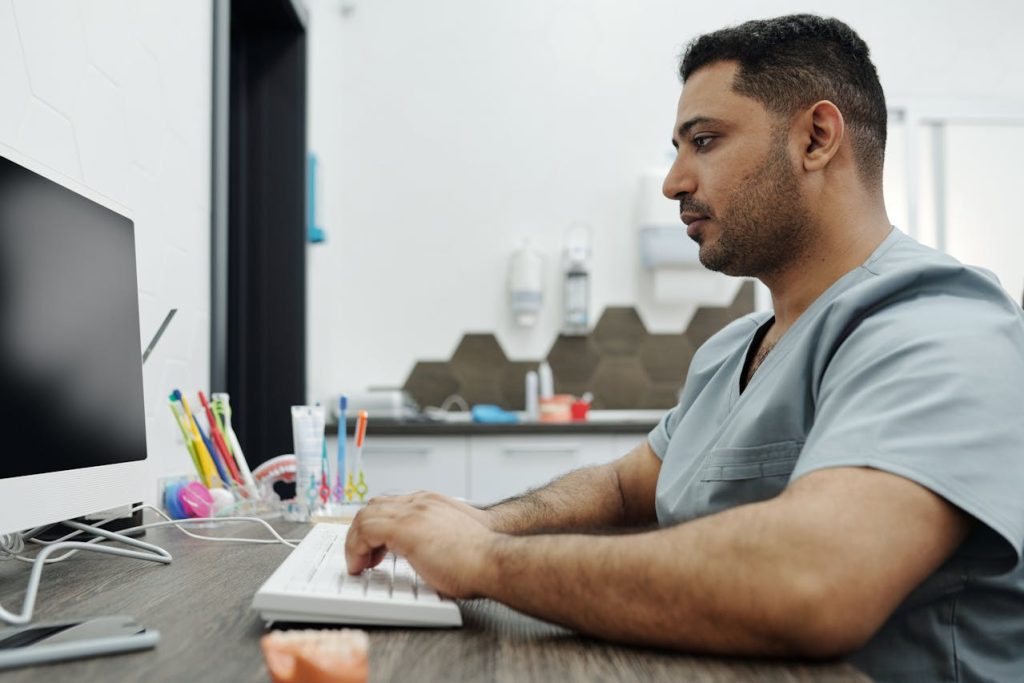 Dentista com computador vendo os principais meios de pagamento online para a sua clínica